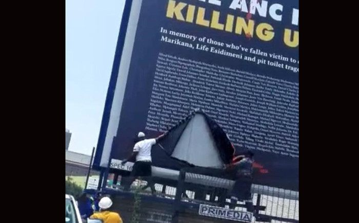 Two men tear the DA's billboard. Picture: @Xondo712/Twitter.