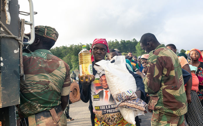 FILE: A picture taken on 18 March 2019 shows villagers receiving food handouts during search and rescue operations in the wake of devastating floods and mudslides caused when Cyclone Idai struck Zimbabwe in Chimanimani. Picture: AFP

