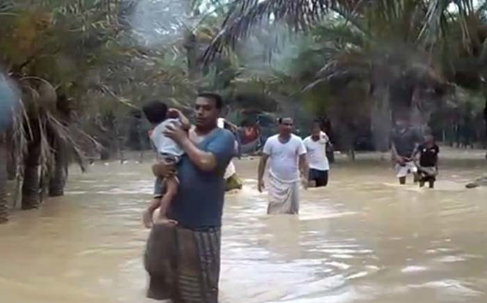 An image grab taken from an AFPTV video shows people walking through flood water as they evacuate a flooded area during a cyclone in the Yemeni island of Socotra. Picture: AFP.