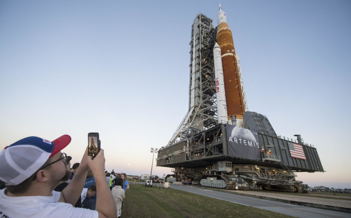 Guests and NASA employees take photos as NASA's Space Launch System rocket with the Orion spacecraft aboard is rolled out of High Bay 3 of the Vehicle Assembly Building on 17 March 2022.