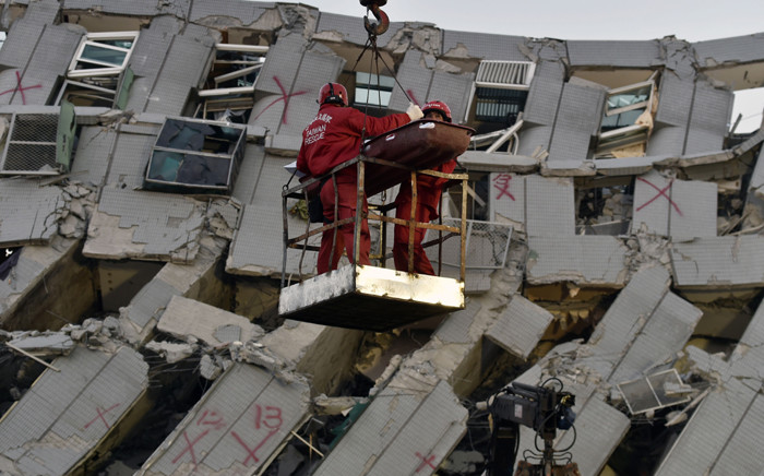 Two rescue workers bring down a victim from the collapsed Wei Kuan complex building in Tainan, southern Taiwan, on February 7, 2016, following a strong 6.4-magnitude earthquake that struck early on February 6. Rescuers raced on February 7 to free more than 120 people buried under the rubble of an apartment complex felled by an earthquake in southern Taiwan that left 24 confirmed dead, as an investigation began into the collapse. Picture: AFP.
