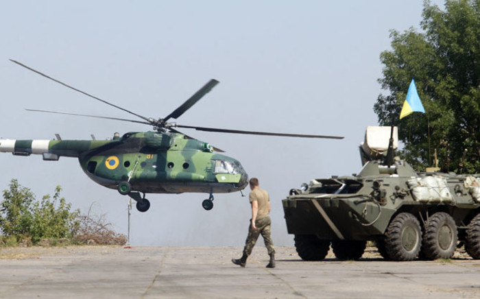 FILE:A serviceman walks near an APC while a helicopter flies on the position of the Ukrainian troops in Donetsk region on 9 August, 2014. Picture: AFP.
