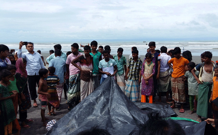 Bangladeshi onlookers watch as a man covers the bodies of Rohingya women and children on 31 August 2017 who drowned after their boat capsized. Picture: AFP
