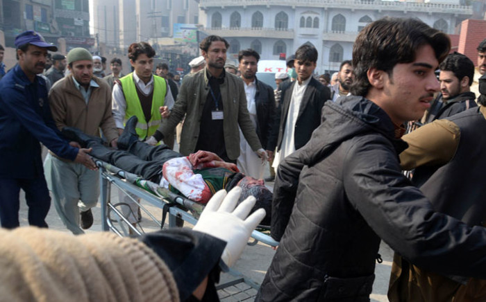 Pakistani men carry an injured student to a hospital following an attack by Taliban gunmen on a school in Peshawar on 16 December, 2014. Picture: AFP.