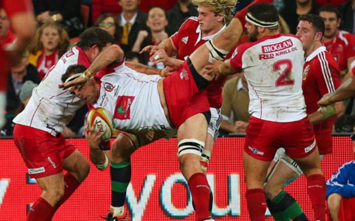 Reds player Jake Schatz (C) is tackled during the rugby union tour match between the Queensland Reds and the British and Irish Lions at Suncorp Stadium in Brisbane on 8 June 2013. Picture: AFP/Patrick Hamilton