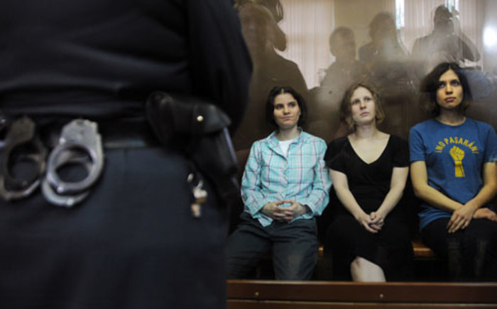 Members of the all-girl punk band "Pussy Riot" Yekaterina Samutsevich (L), Maria Alyokhina (C) and Nadezhda Tolokonnikova (R) sit in a glass-walled cage during a court hearing in Moscow. Picture: AFP