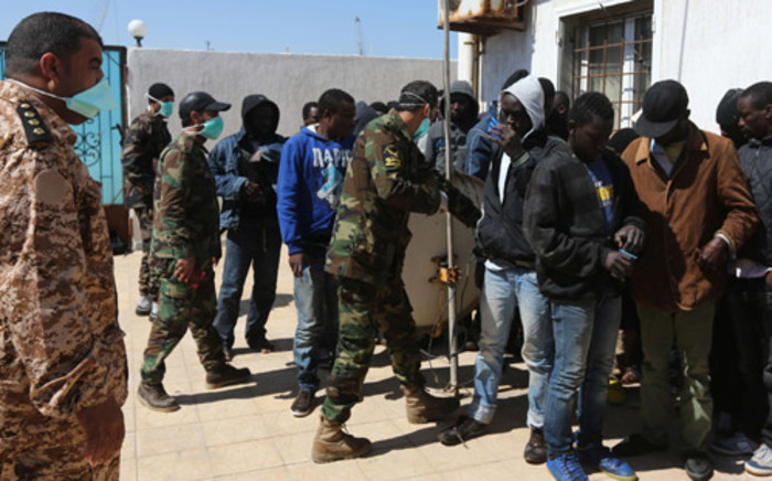 FILE: African migrants wait at a Libyan Naval forces post in Tripoli on 10 April 2014 after their boat was intercepted en route to Europe and brought back to Libya. Picture: AFP.