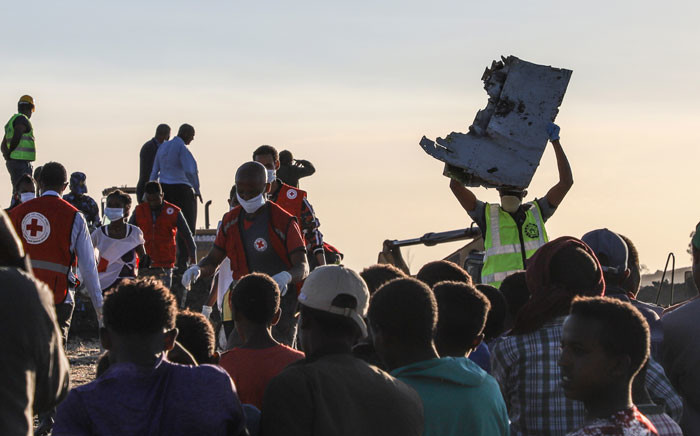 FILE: A man carries a piece of debris on his head at the crash site of a Nairobi-bound Ethiopian Airlines flight near Bishoftu, a town some 60 kilometres southeast of Addis Ababa, Ethiopia, on 10 March 2019. Picture: AFP