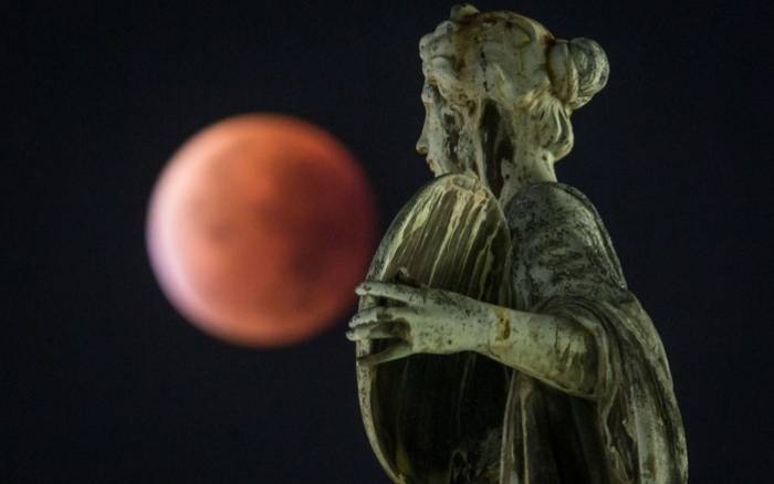 The supermoon or blood moon seen behind a statue during a total lunar eclipse in Frankfurt am Main, Germany. West, September 28, 2015. Photo: AFP. 