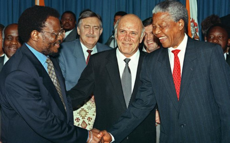 FILE: Presiden Afrika Selatan Frederik W. De Klerk (tengah) tersenyum sementara pemimpin ANC Nelson Mandela (kanan) dan pemimpin IFP Mangosuthu Buthelezi berjabat tangan setelah mereka menandatangani kesepakatan di Union Buildings di Pretoria 19 April 1994. Pik Botha, Orang Asing Afrika Selatan Menteri Urusan (C, baris ke-2) melihat ke atas.  foto: AFP.