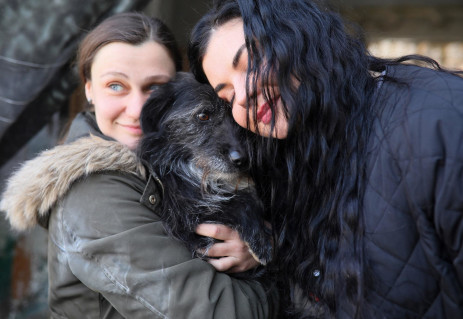 Women hug a dog in the "Home for Rescued Animals" shelter in the western Ukrainian city of Lviv on 26 March 2022.