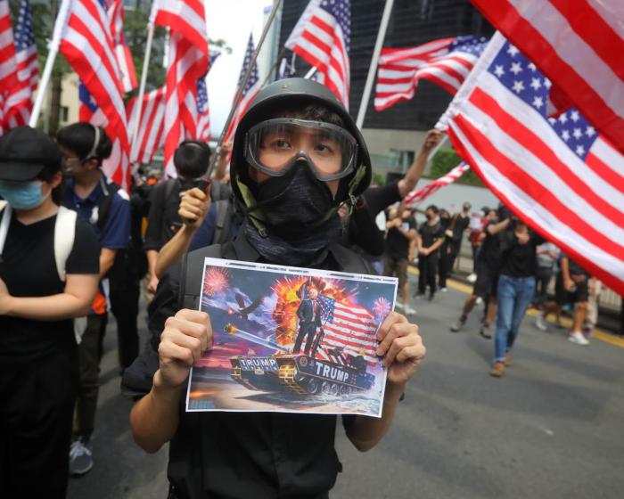 A man holds a placard as protesters wave US national flags while they march from Chater Garden to the US consulate in Hong Kong on 8 September 2019, to call on the US to pressure Beijing to meet their demands and for Congress to pass a recently proposed bill that expresses support for the protest movement. Pro-democracy activists planned to rally outside the US consulate in Hong Kong on 8 September as they try to keep international pressure on Beijing following three months of huge, sometimes violent, protests. Picture: AFP