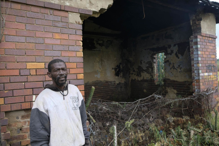 Tebogo Nkadu stands outside his home, which has been almost entirely destroyed by constant flooding in Kliptown.