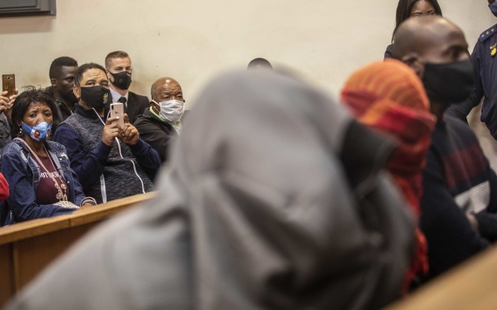 Family of members of Nathaniel Julies look at the three police officers accused of his murder during an appearance in court.