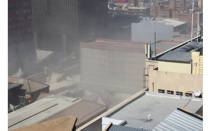 A dust cloud rose as the cement and concrete fell to the ground. Picture: Ahmed Kajee/EWN