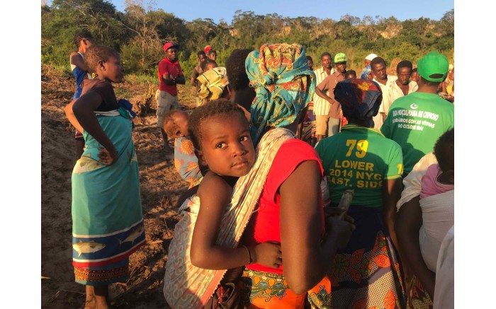 A baby on his mother’s back as she stands in line to receive aid.