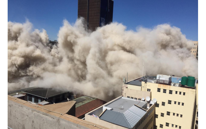 A dust cloud rose as the cement and concrete fell to the ground. Picture: Ahmed Kajee/EWN