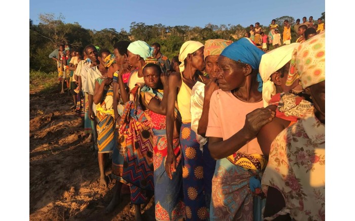 Victims of Cyclone Idai stand in line to receive food and water from the relief boats next to the Buzi River.