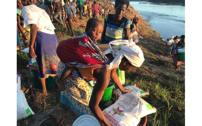 A mother gathers her food and water she received from the relief workers.