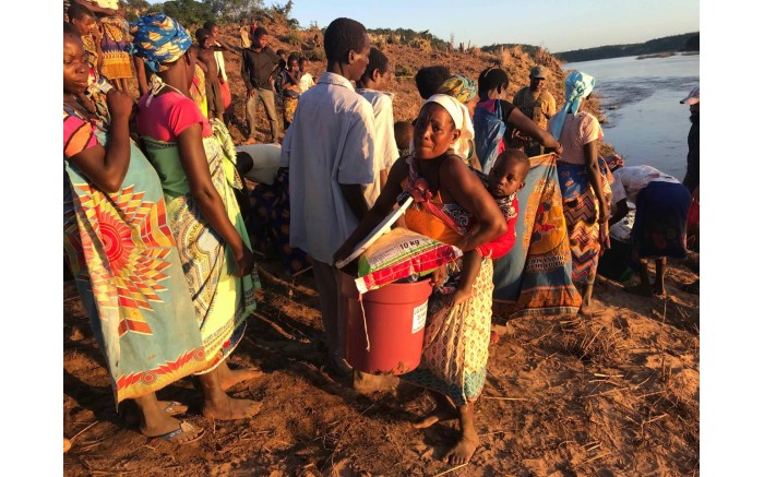 A mother struggles up a steep hill on the edge of the Buzi River after receiving food and water from relief workers.