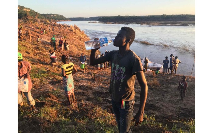 A man from a village close to the edge of the Buzi River drinks water after receiving food and water from relief workers.