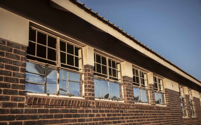 Broken windows, covered with zinc, are all over the school buildings.