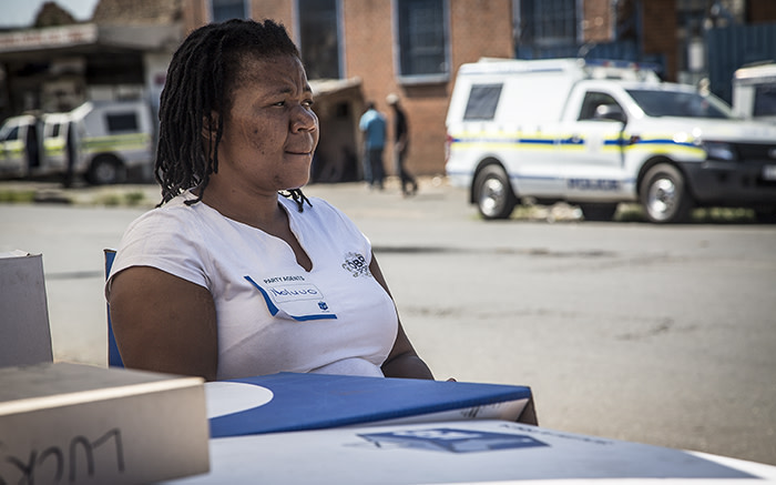 An IEC official sits at a temporary registration station in Denver as police watch over the area. Picture: Reinart Toerien/EWN