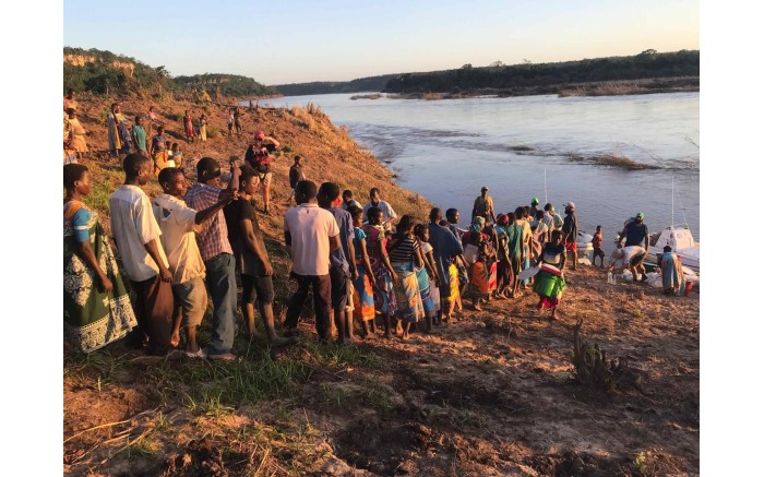 Victims of Cyclone Idai stand in line to receive food and water from the relief boats next to the Buzi River.